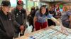 A woman leans over a table top onto which is projected a street map; some of the projection is on her outstretched arm. Two museum visitors, both young men, are attentive as the woman explains the exhibit.