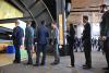 Seven students in business professional attire stand in line while waiting to talk to a company recruiter.