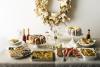 A table of holiday food with a wreath hanging above the table. 