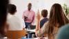 A student raising her hand to ask a professor a question during class.